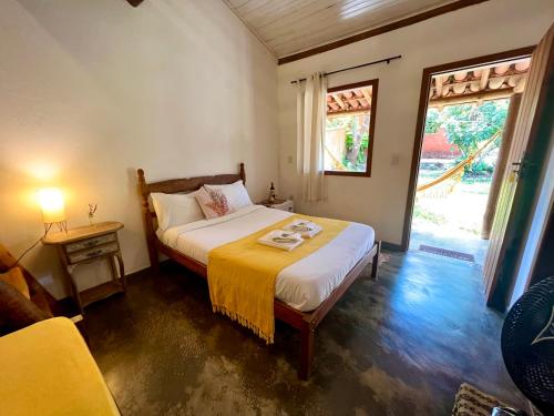 a bedroom with a bed with a yellow blanket on it at Pousada Refazenda - Milho Verde in Milho Verde