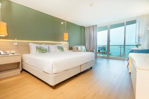 a bedroom with a large white bed and a balcony at Grand Sirenis San Andres in San Andrés