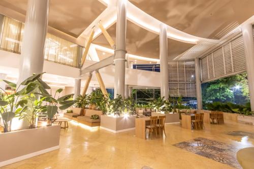 a lobby with potted plants and tables and chairs at Grand Sirenis San Andres in San Andrés