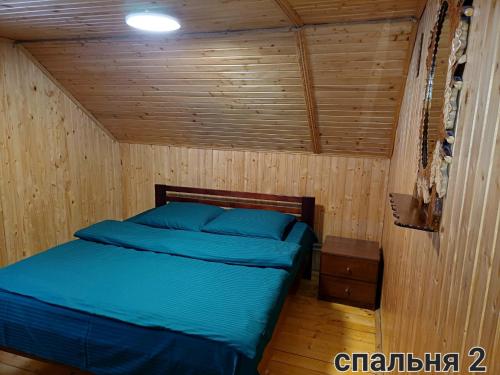 a bedroom with a bed in a wooden room at Cottage Panorama Karpat in Volosyanka