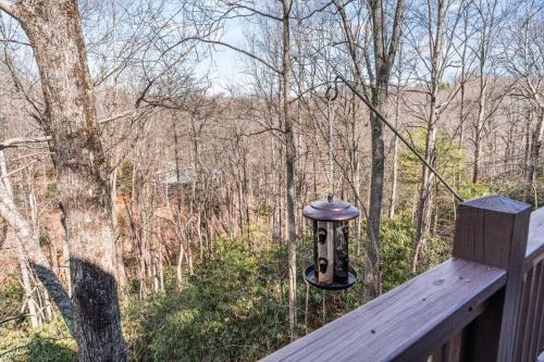 a bird feeder sitting on a wooden deck in the woods at Spacious Lakeview Mountain Cabin in Powderhorn Mountain