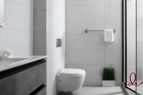 a white bathroom with a toilet and a sink at דירה עם מרפסת על יד הים - By Edomlux in Eilat
