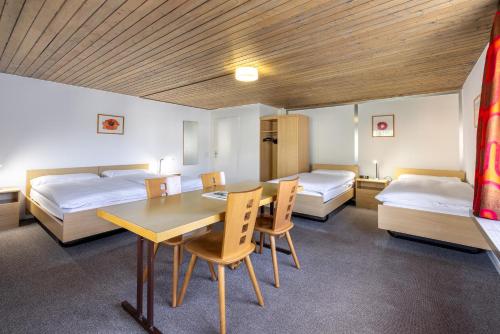 Habitación con 2 camas, mesa y sillas en Hostel Casa Franco en St. Moritz