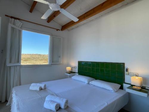 a white bedroom with two beds and a window at Villa Pont d'En Gil in Cala en Blanes