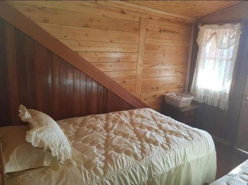 a bedroom with a bed with a wooden wall at Hospedaje Lojada in Oxapampa