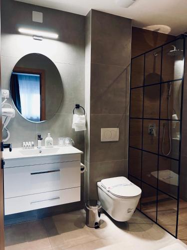 a bathroom with a toilet and a sink and a mirror at MOZAIK APARTMENTS & SPA - Modern 4-Star Apartments with Exclusive Private SPA WELLNESS in the City Center - SAUNA, JACUZZI, TURKISH BATH - FREE PARKING, Wi-FI - Rooms & Apartments Cuprija in Ćuprija