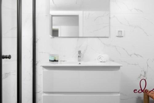 a white bathroom with a sink and a mirror at Modern family apartment next to the sea - By Edomlux in Eilat