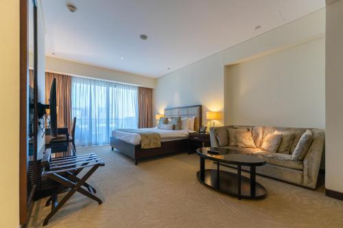 a hotel room with a bed and a couch at Spacious, Modern Studio in Marina Dubai in Dubai