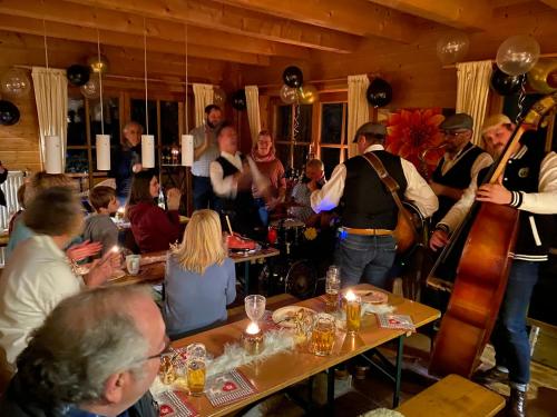 grupa ludzi siedzących przy stolikach w restauracji w obiekcie Ferienhaus Alpenpanorama Chalet w mieście Mollenberg