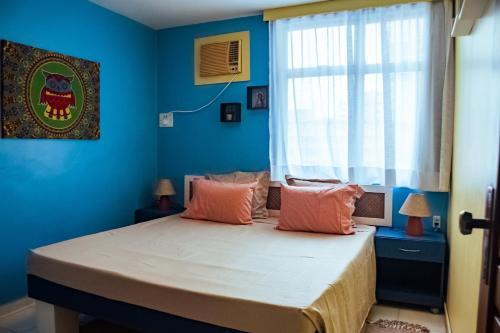 Schlafzimmer mit einem Bett mit blauen Wänden und einem Fenster in der Unterkunft Apto a 350m da Praia de Ponta Verde, em Maceio AL in Maceió