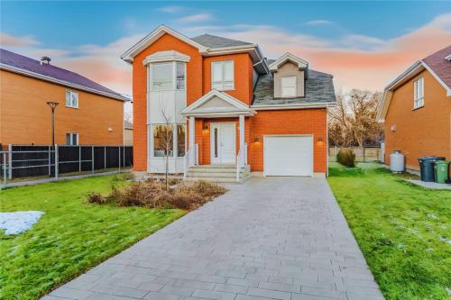 una casa naranja con un garaje blanco en un patio en Spacious Home! 5 King Beds, 1 Queen, Modern Luxury, Free Parking, en Pointe-Claire