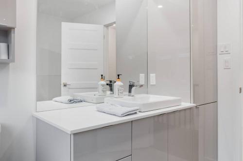 Baño blanco con lavabo y espejo en Spacious Home! 5 King Beds, 1 Queen, Modern Luxury, Free Parking en Pointe-Claire