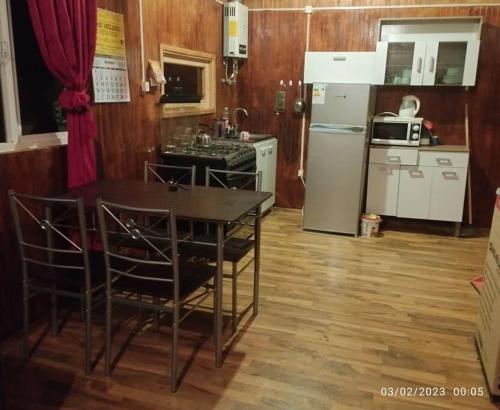 a kitchen with a table with chairs and a refrigerator at Cabañas Don Esteban in Tortel