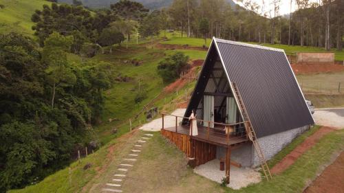 uma casa com um telhado de metal no topo de uma colina em Cabana Vale Encantado em São Bento do Sapucaí