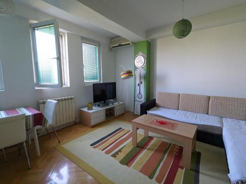uma sala de estar com um sofá e um relógio na parede em Artistica Apartment Skopje, 2 bdr em Skopje