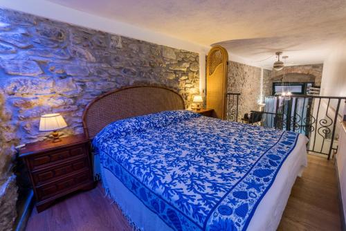 a bedroom with a blue bed and a stone wall at The Vernazza Main Plaza - Rooms & Suites in Vernazza