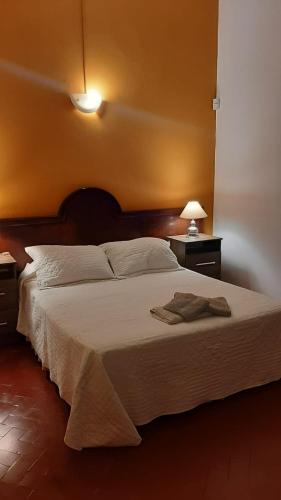 1 dormitorio con 1 cama grande con sábanas blancas y lámpara en La Manquel - Casa y Yungas en Yerba Buena
