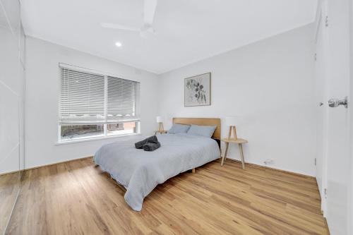 a white bedroom with a bed and a window at Cheltenham Delight - Renovated Two Bedroom Unit in Cheltenham