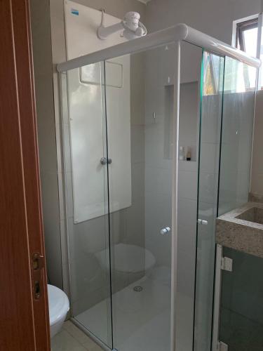 a glass shower in a bathroom with a toilet at Flat Porto do Galo in Porto De Galinhas