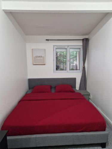 a bedroom with a bed with red sheets and a window at maison individuelle à Drancy in Drancy