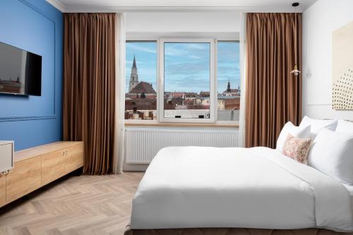 a bedroom with a large bed and a large window at Siesta Boutique Smart Suites in Cluj-Napoca