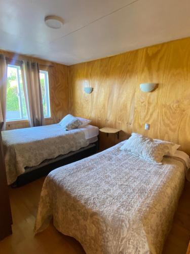 a hotel room with two beds and two windows at Cabaña Pradera Premiun I in Llau-Llao