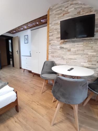 a room with a table and chairs and a tv at Apartament Góralski Duet 8-osobowy - apartament na wyłączność in Bukowina Tatrzańska