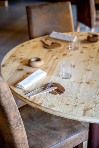 a wooden table with utensils on top of it at Au Charmant Petit Lac - Ecohotel Parc & Spa in Champoluc