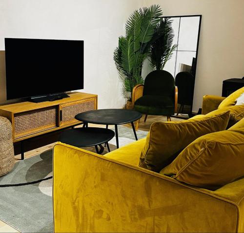 a living room with a yellow couch and a tv at la madrague des 2 caps in Audembert