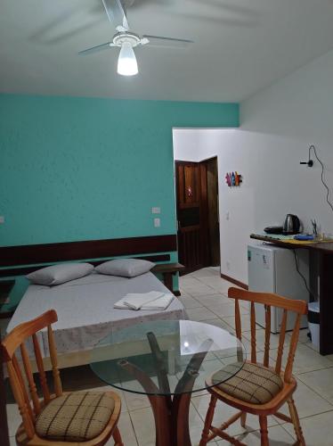 a bedroom with a bed and two chairs and a glass table at Suites Brilho do Sol in Ubatuba