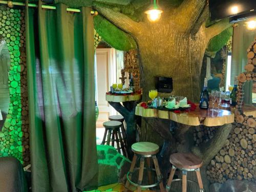 um quarto com um bar com temática de árvore, bancos e uma mesa em Hotel Boutique El Duende Mantagua em Quintero