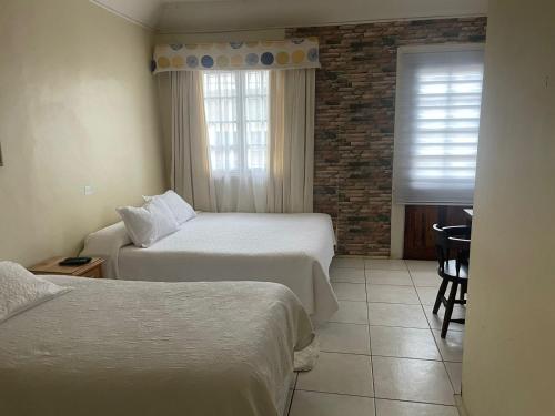Una habitación de hotel con dos camas y una ventana. en Hotel Palermo Quintero, en Quintero