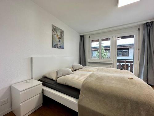 a white bedroom with a bed and a window at Panorama apartment for 4 near Zermatt in Täsch