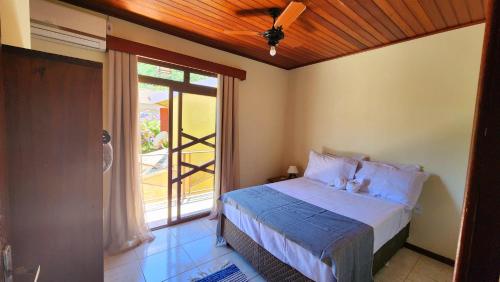 um quarto com uma cama e uma grande janela em Partiu Praia SC em Guarda do Embaú