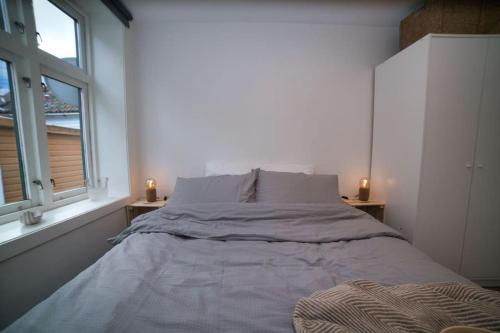 Cama en habitación blanca con 2 ventanas en Vestre Murallmenningen, en Bergen