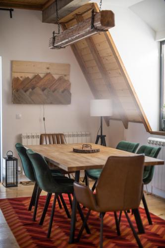 a wooden table with green chairs in a room at Kežman Mountain Houses in Kopaonik