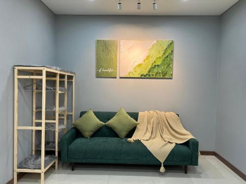 a green couch in a living room with a painting at UPhoenix Home- HaDo Centrosa Garden in Ho Chi Minh City