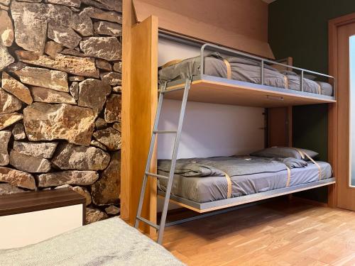 een slaapkamer met een stapelbed voor een stenen muur bij Apartmán Medvědín 100 in Špindlerův Mlýn