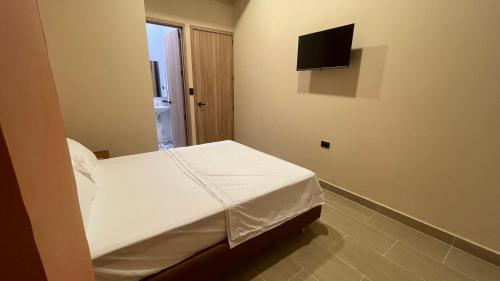 een slaapkamer met een bed en een tv aan de muur bij Awa House Hotel in Aguachica