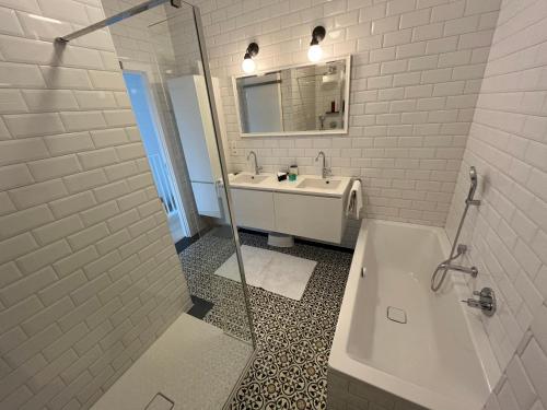 y baño blanco con lavabo, bañera y ducha. en Luxury apartment, private terrace & FREE PARKING, en Amberes