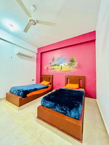 two beds in a room with a painting on the wall at Nukud guest house in Aswan