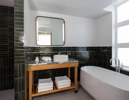 a bathroom with a tub and a sink and a mirror at Kissel Uptown Oakland, in the Unbound Collection by Hyatt in Oakland