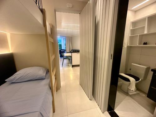 een kleine slaapkamer met een bed en een hal bij Flat Luxo - Pé na Areia - Maui Beach Residence in Tamandaré