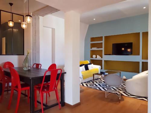 une salle à manger et un salon avec des chaises rouges et une table noire dans l'établissement Appartement Design Rouen-gare avec parking privé, à Rouen