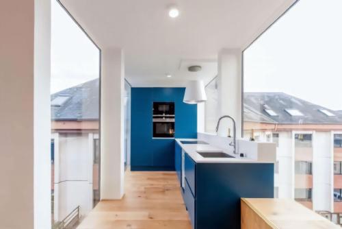 - une cuisine avec des comptoirs bleus et blancs et de grandes fenêtres dans l'établissement Appartement Design Rouen-gare avec parking privé, à Rouen