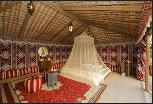 Al Marmoom Oasis “Luxury Camping & Bedouin Experience” في دبي: غرفة بسرير وسجادة حمراء