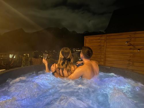 a man and a woman sitting in a hot tub at Wierchowe Domki z jacuzzi in Kościelisko