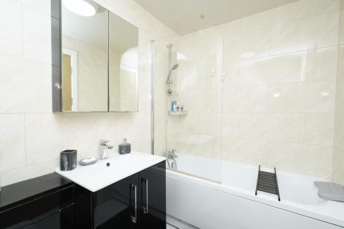 y baño con bañera blanca, lavamanos y bañera. en Luxe & Stylish Central Luton 2Bed Apt - Fast Wi-Fi & Private Patio en Luton