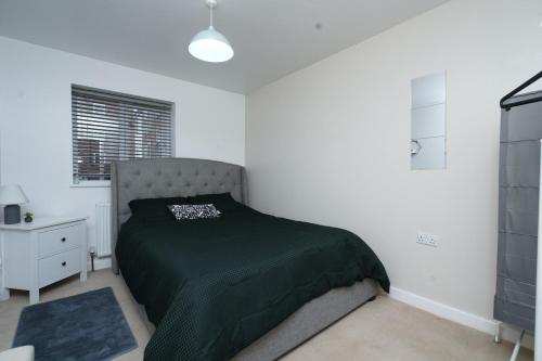 a bedroom with a bed with a green blanket at Luxe & Stylish Central Luton 2Bed Apt - Fast Wi-Fi & Private Patio in Luton