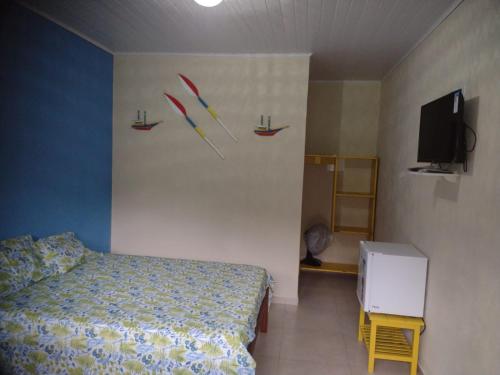 a bedroom with a bed and a tv on a wall at Pouso AJH in Paraty